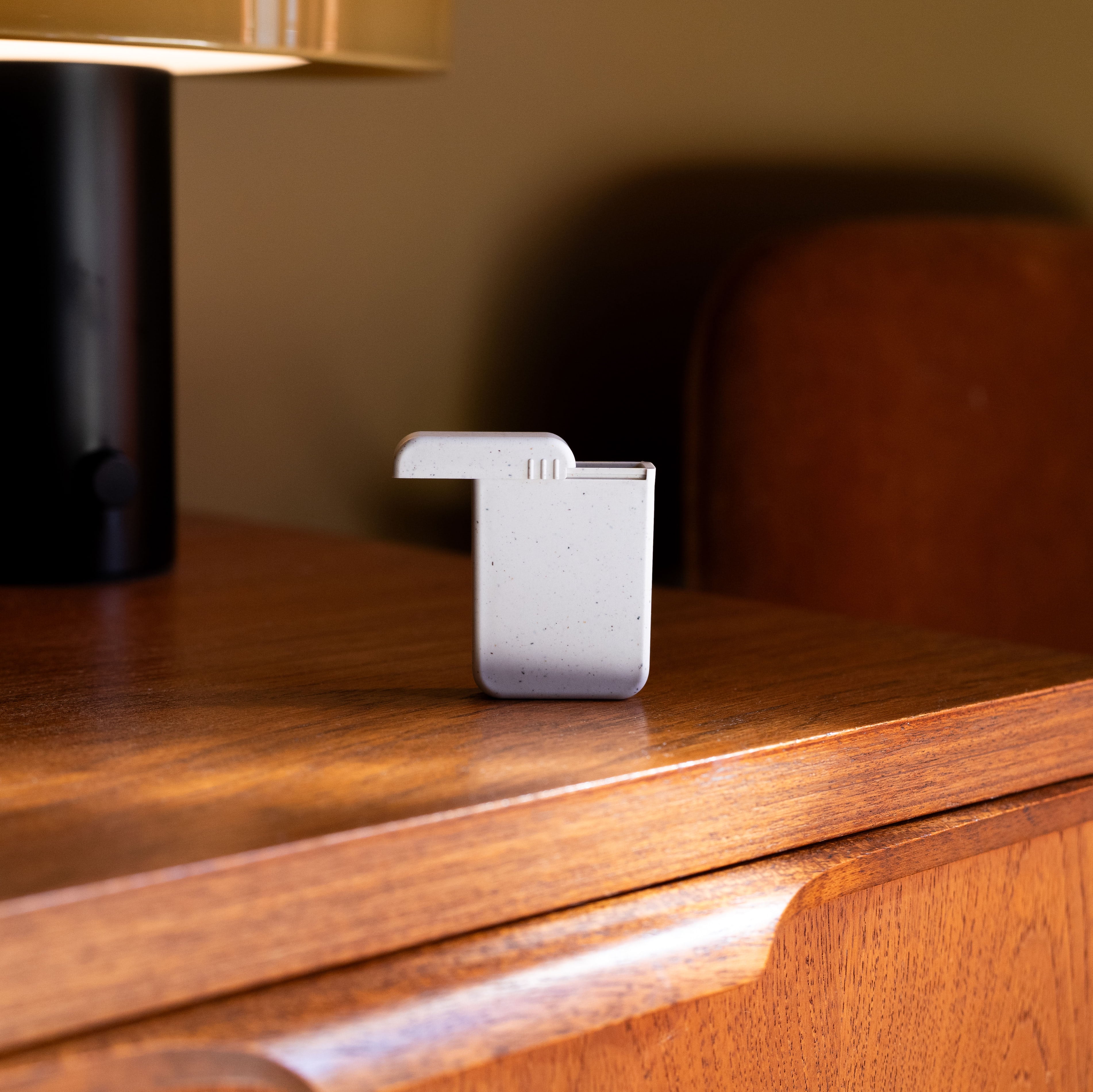 AndAround travel pill case on a wood table.