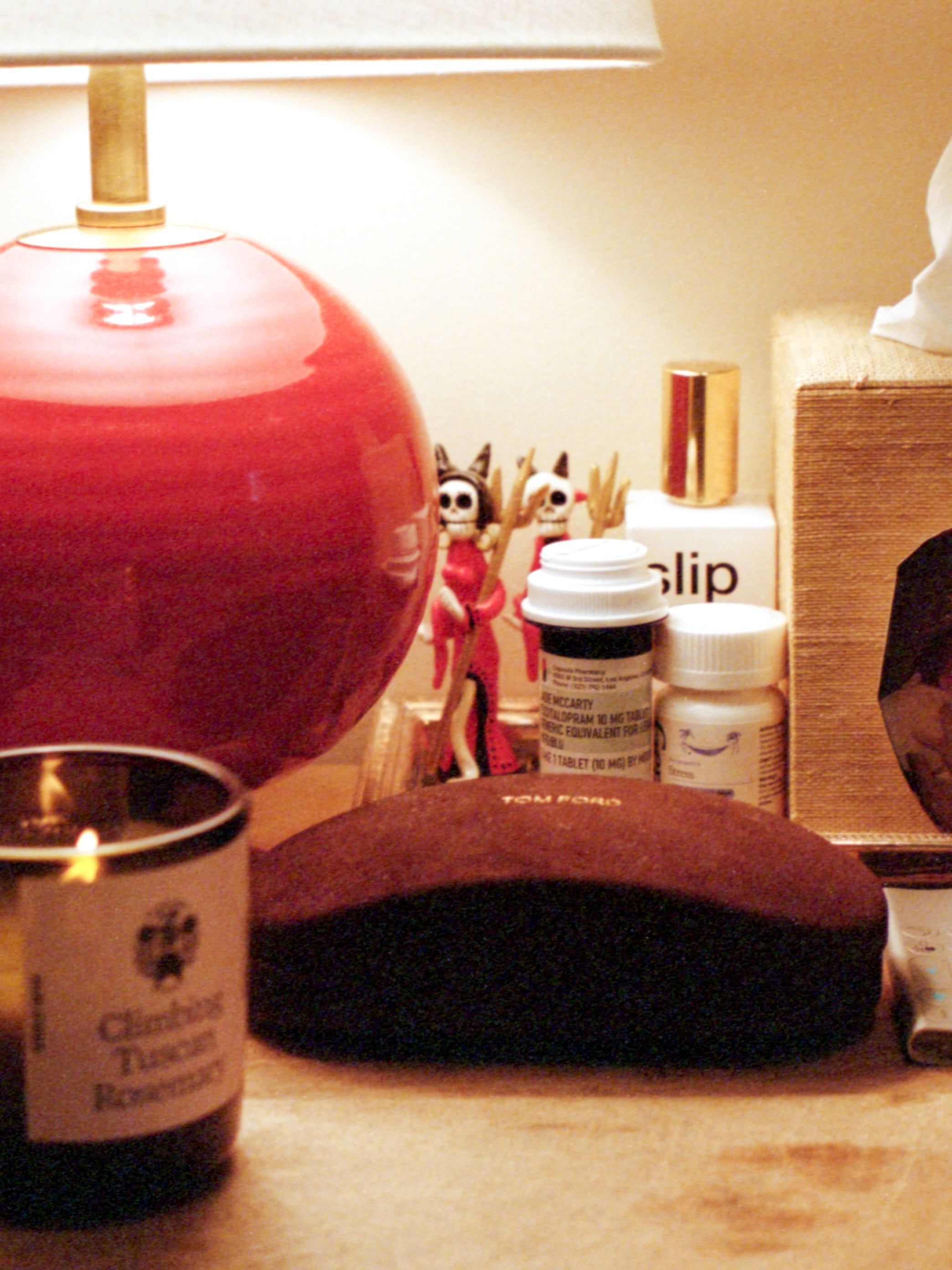 Jade Iovine's bedside table with a lamp, medicine, a candle and candle